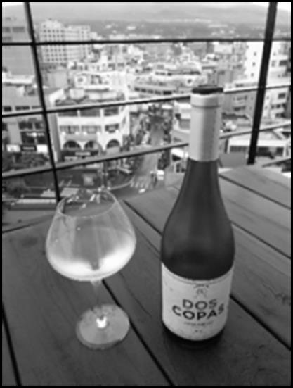 Flasche und Weinglas mit dem Aguirre Chardonnay Dos Copas 2018, hoch über der südkoreanischen Hafenstadt Seogwipo.
